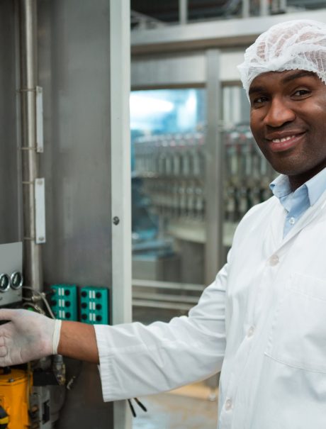 Portrait of confident male worker operating machine in juice factory Portrait of confident male worker operating machine in juice factory